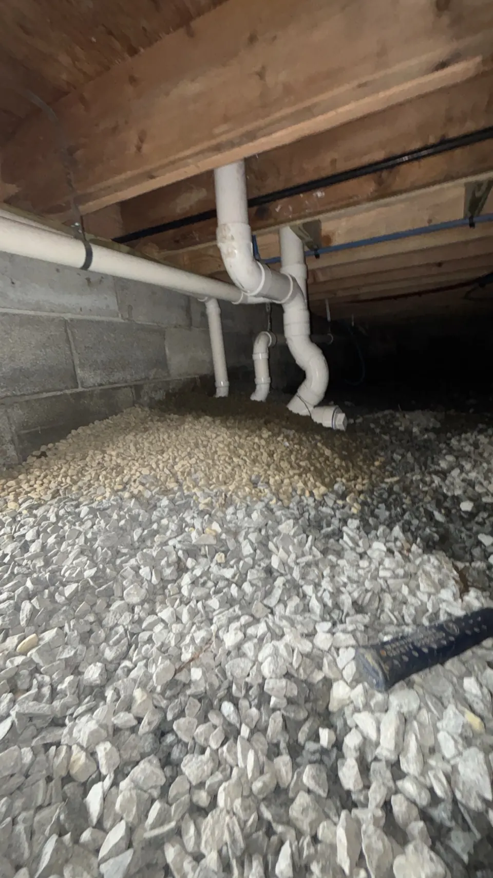 Drain and water piping beneath exposed floor framing in a West Yarmouth home