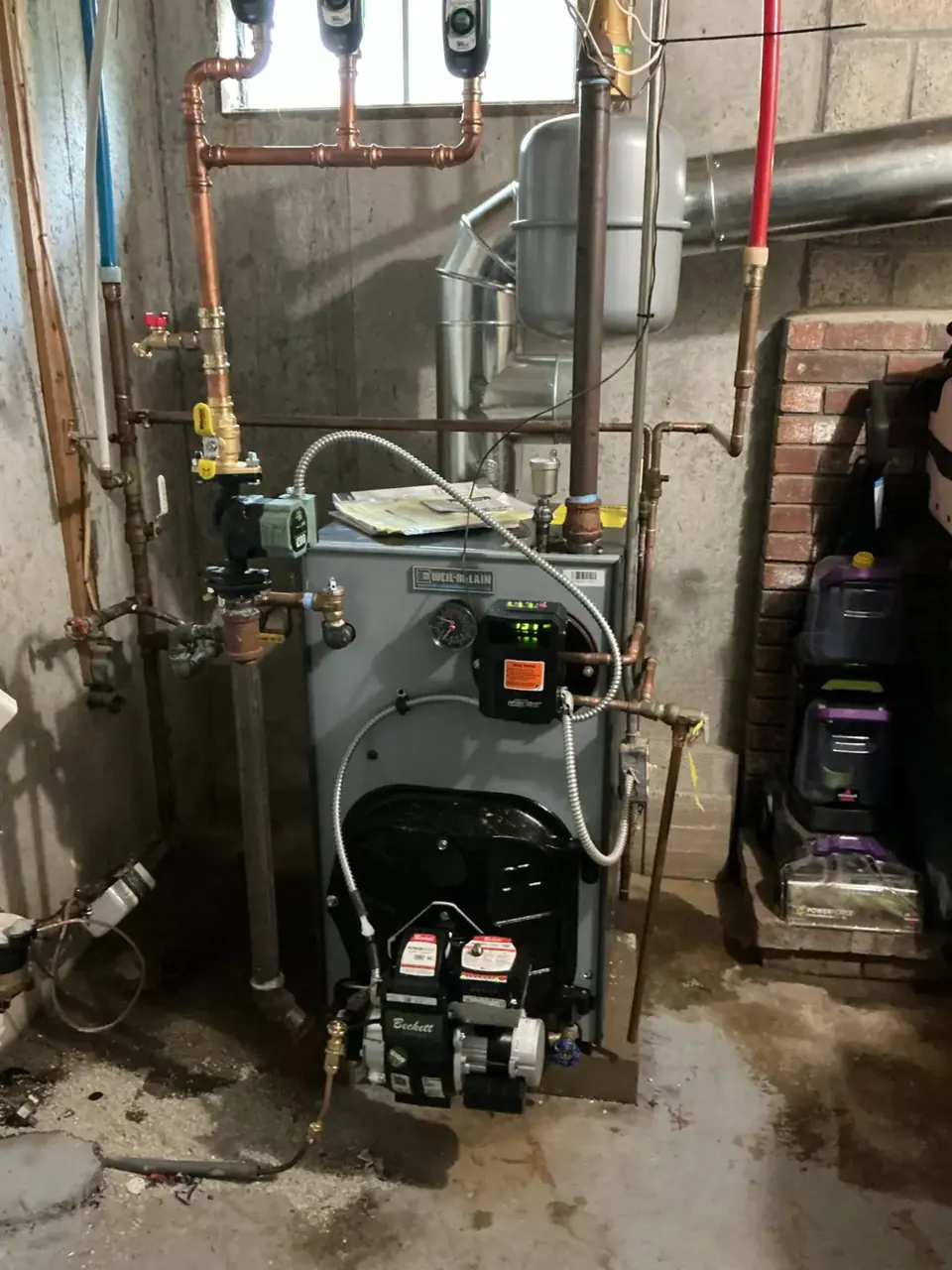 Weil-McLain oil boiler with a Beckett burner and connected heating pipes