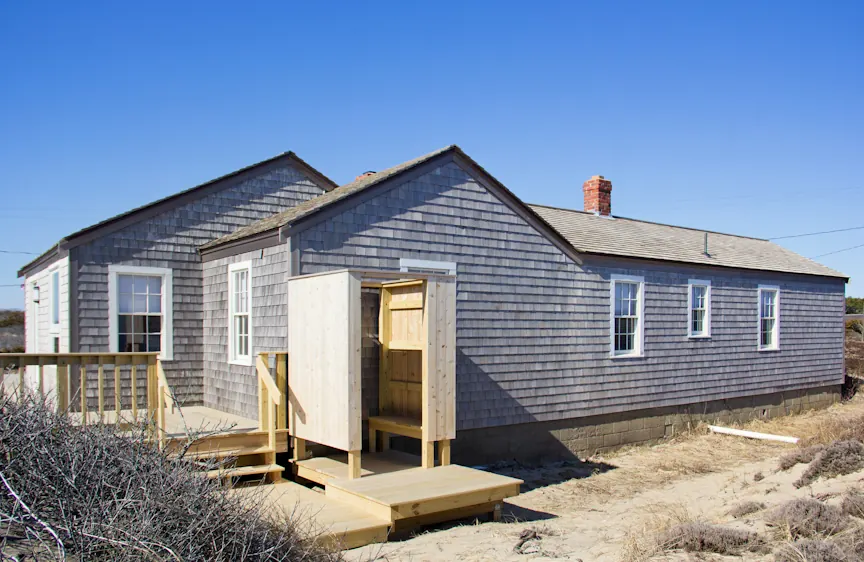 Wooden outdoor shower enclosure beside a shingled cottage at Cape Cod National Seashore