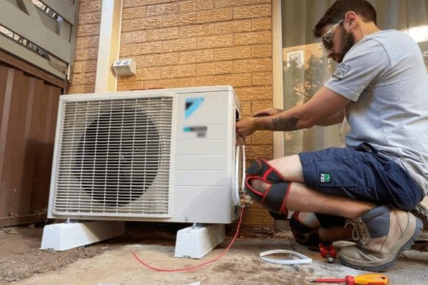 Technician installing a ductless mini split air conditioning unit outdoors, demonstrating professional service for heating and cooling solutions.