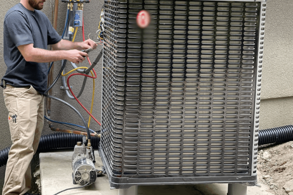 Technician servicing a heat pump unit, emphasizing HVAC maintenance and installation services by Durfee Plumbing & Heating LLC.