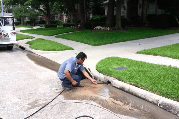 Plumber using advanced equipment for drain cleaning in residential area, ensuring smooth water flow and preventing clogs.