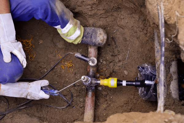 Plumber working on gas line installation in a trench, featuring tools and pipes, highlighting Durfee Plumbing & Heating LLC services.