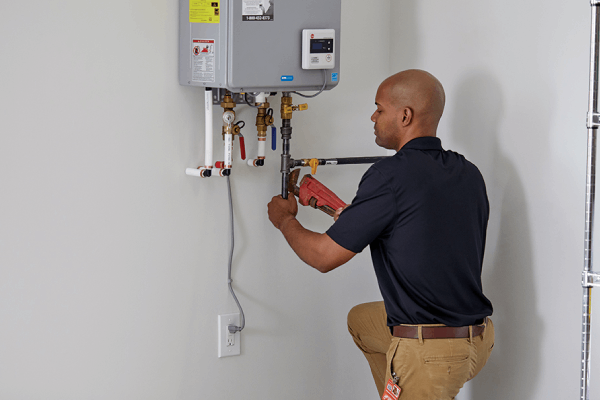 Professional technician performing plumbing installation on a tankless water heater, showcasing quality service by Durfee Plumbing & Heating.